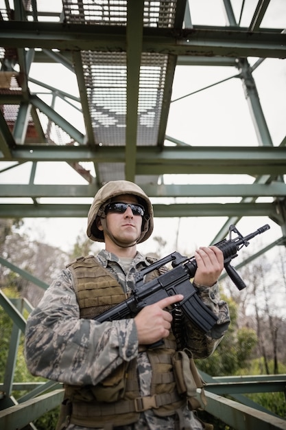 Foto soldado militar guardando com um rifle no campo de treinamento