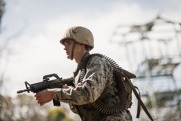 Soldado militar de pie con un rifle en el campo de entrenamiento