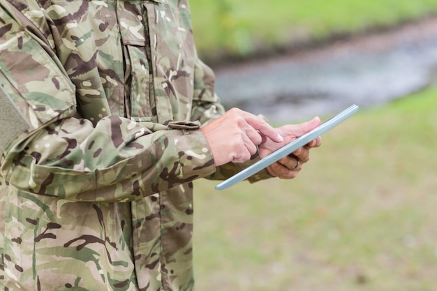 Soldado mirando tablet pc en el parque