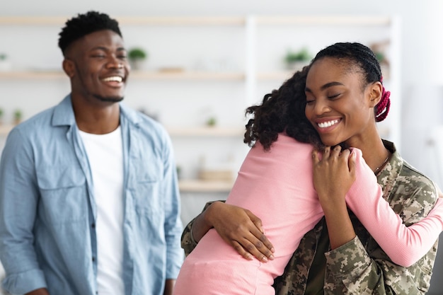 Soldado mujer negra abrazando a su hija en casa