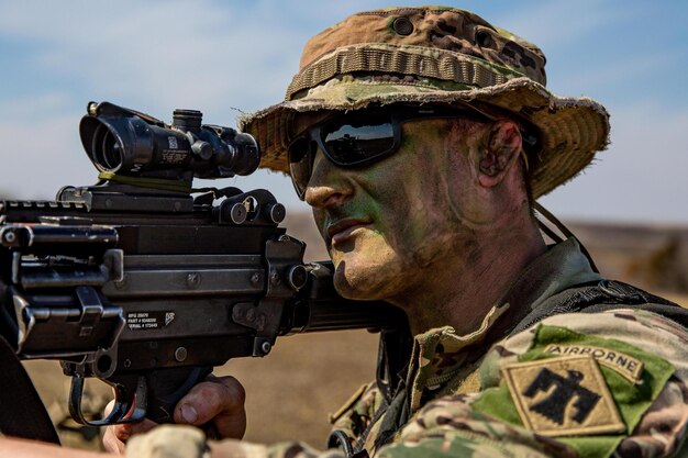 Un soldado que lleva un sombrero de camuflaje y gafas de sol sostiene una pistola con el número 7.