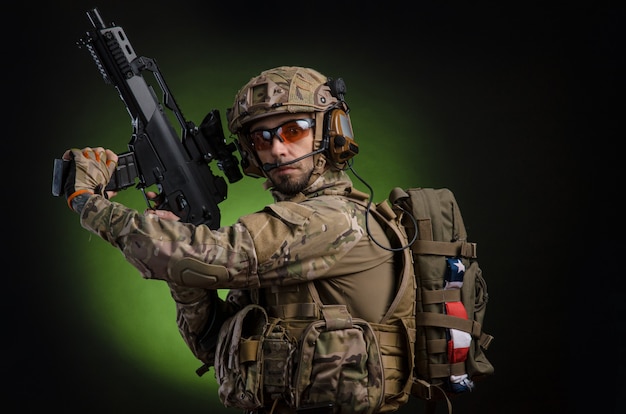 Un soldado en ropa militar con un arma sobre un fondo oscuro