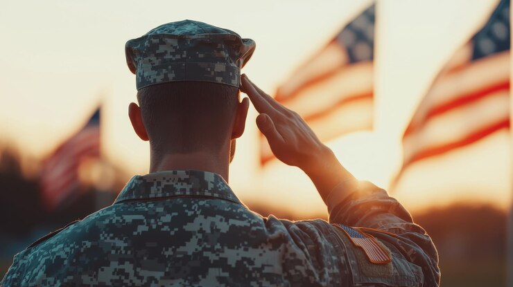 soldado saludando con orgullo mientras las banderas ondean en el fondo durante la puesta del sol que simboliza el honor y el respeto por el servicio