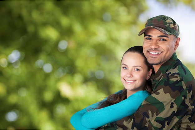 Soldado sonriente con su esposa de pie contra el fondo