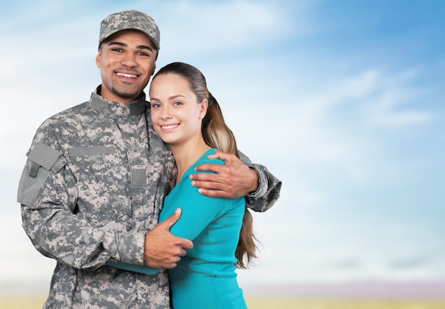 Soldado sonriente con su esposa de pie contra el fondo