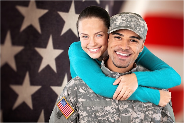 Foto soldado sorridente com sua esposa em pé contra o fundo da bandeira americana