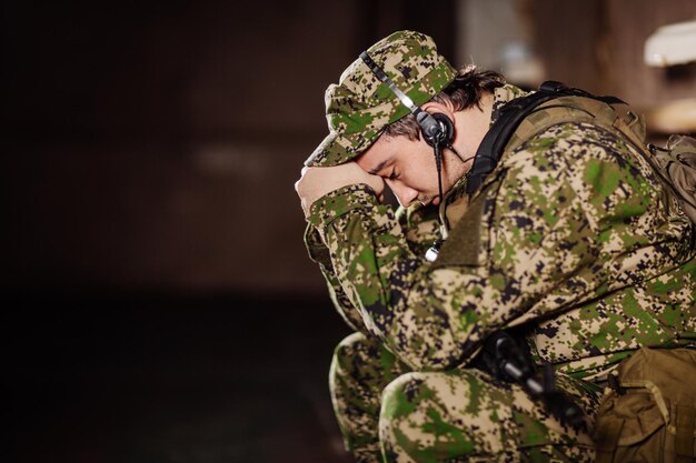 Soldado triste sentado com um rifle preto