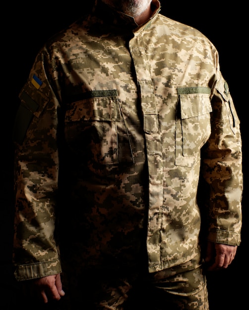 Foto soldado ucraniano vestido con uniforme está parado en la oscuridad