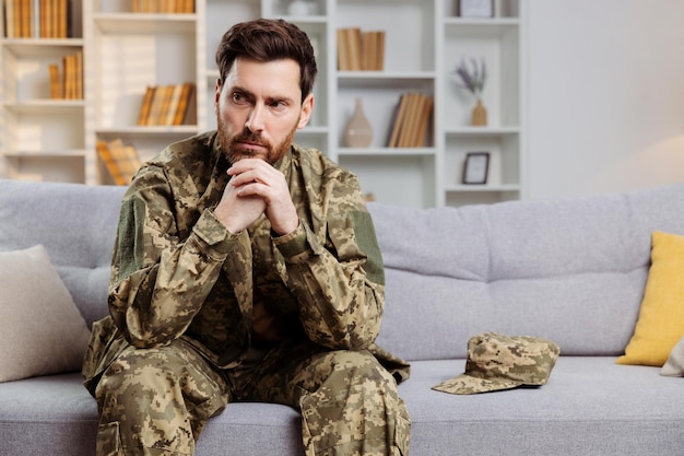 Soldado voltando para casa tema Homem angustiado em equipamento do exército ucraniano sentado sozinho em um sofá