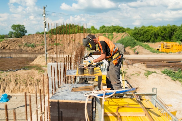 Foto soldador constructor soldando una estructura metálica en un sitio de construcción mientras construye un puente