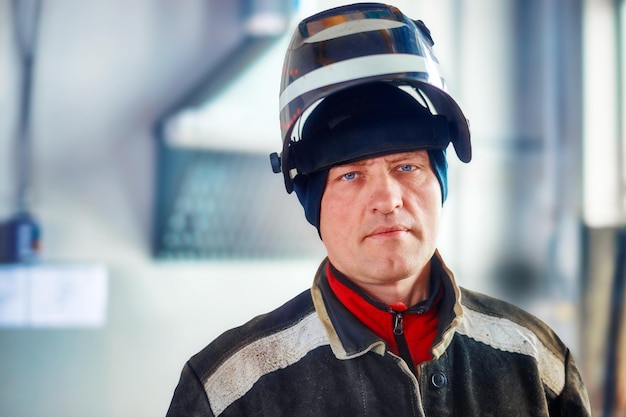 Soldador masculino em roupas de trabalho com máscara na cabeça olha diretamente para a câmera retrato autêntico do trabalhador