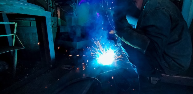 Soldador de metal de soldadura con máquina de soldadura de arco de argón y tiene chispas de soldadura. Un hombre usa máscara de soldadura y guantes protectores. Seguridad en el lugar de trabajo industrial. Soldador trabajando con seguridad. Industria metalúrgica.