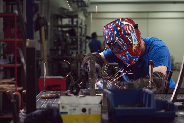 Soldador profesional de la industria pesada que trabaja dentro de la fábrica usa casco y comienza a soldar con enfoque selectivo