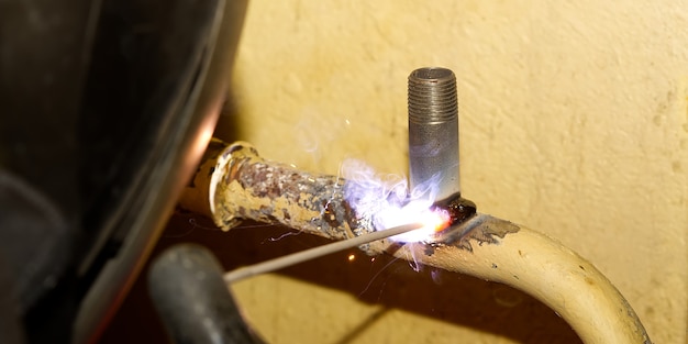 Soldador profesional de soldadura con tubos de metal viejos eléctricos para calefacción. Concepto de renovación del sistema de calefacción antiguo