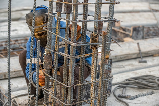 Un soldador en el sitio de construcción hace una estructura metálica para verter hormigón