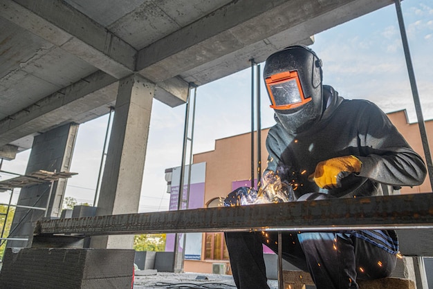 Un soldador de trabajo hace una estructura metálica en una nueva infraestructura de construcción