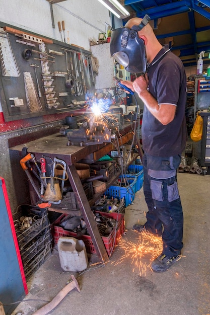 Soldador trabalhando com lança elétrica na oficina.