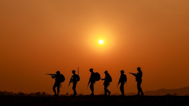 Soldados de ação de silhueta andando e segurando o fundo das armas é o efeito do navio de balanço branco do pôr do sol