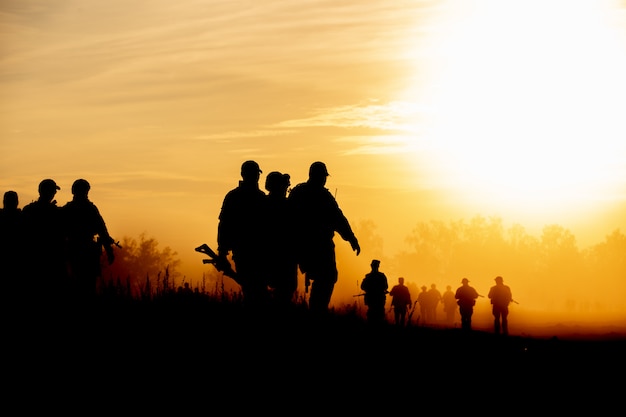 Soldados de ação de silhueta andando segurando armas é fumaça e pôr do sol e efeito de navio de balanço de branco estilo de arte escura