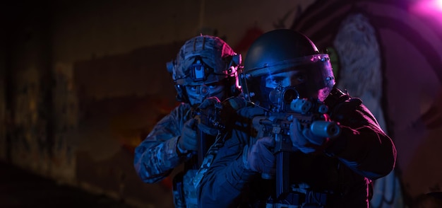 Soldados de guerra modernos no escuro com munições de combate e armas nas mãos de miras a laser equipadas estão em ordem de batalha. Mídia mista. Foto de alta qualidade