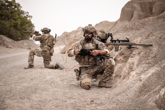 Soldados em uniformes de camuflagem apontando com seus rifles prontos para disparar durante uma operação militar