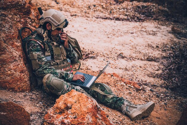 Soldados de fuerzas especiales en guerras en el desierto Gente de Tailandia Soldado del ejército usa una computadora portátil para ver el mapa con satélite Uso de radio para comunicación durante la operación militar