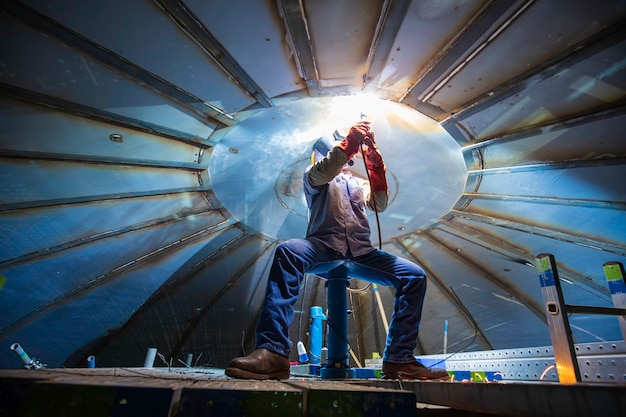 La soldadura de arco de metal de trabajador masculino es parte del tanque de techo de la construcción del tanque de almacenamiento de petróleo y gas dentro de espacios confinados.