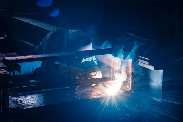 Soldadura de estructuras de acero y chispas brillantes en la industria de la construcción. Tono azul