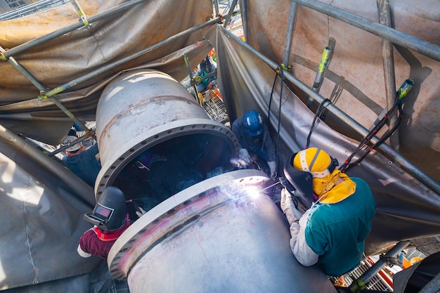 La soldadura de metal de trabajador masculino es parte de la maquinaria de construcción de grandes oleoductos, petróleo y gas.