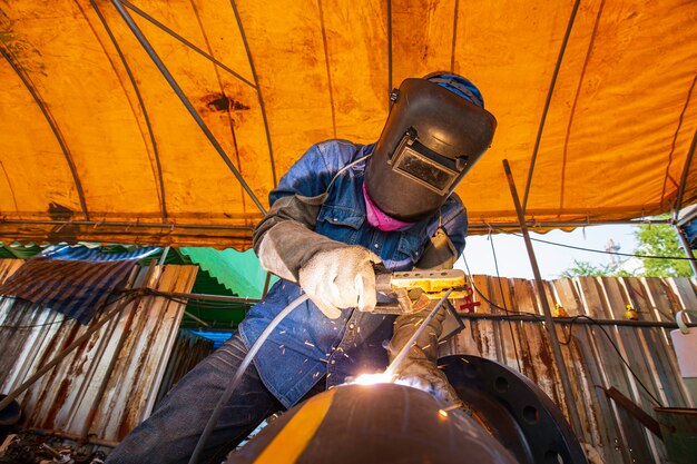 Soldadura de metal trabajador masculino es parte de la maquinaria de construcción de tuberías de boquillas de petróleo y gas