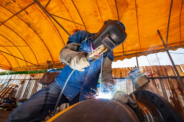 Soldadura de metal trabajador masculino es parte de la maquinaria de construcción de tuberías de boquillas de petróleo y gas