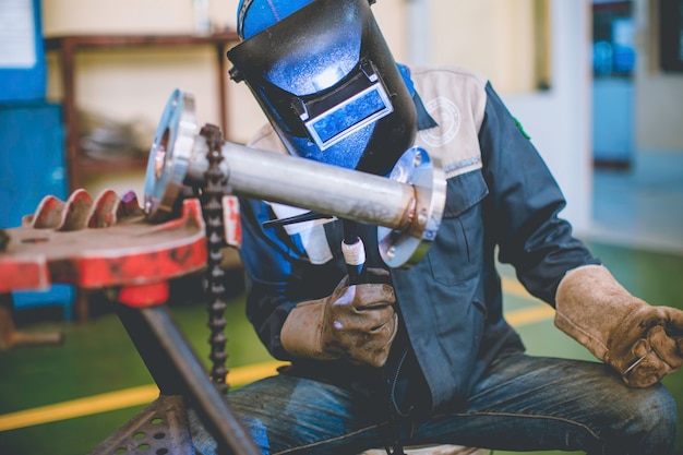 Soldadura de metal trabajador masculino es parte de la maquinaria de construcción de tuberías de boquillas de petróleo y gas