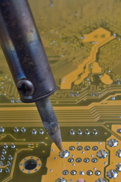 Foto soldadura de placa de circuito electrónico con componentes electrónicos. los ingenieros reparan la placa de circuito con soldador.