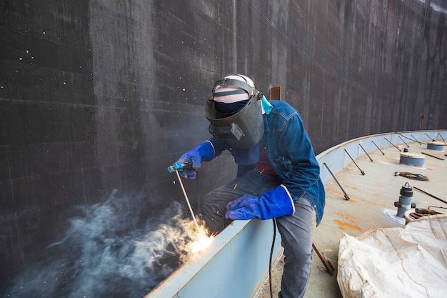 Soldagem de metal do trabalhador masculino é parte da barragem de espuma da construção da viga do tanque da placa de máquinas fumaça dentro de espaços confinados