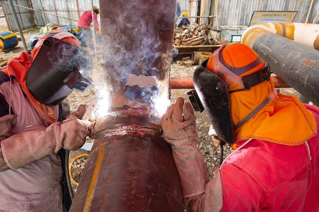 Soldar metal de dois trabalhadores faz parte da construção de um gasoduto de bocal de maquinário, petróleo e gás