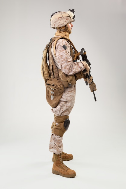 Soldat in der US-Marineuniform mit Gewehr auf hellgrauem, Atelieraufnahme