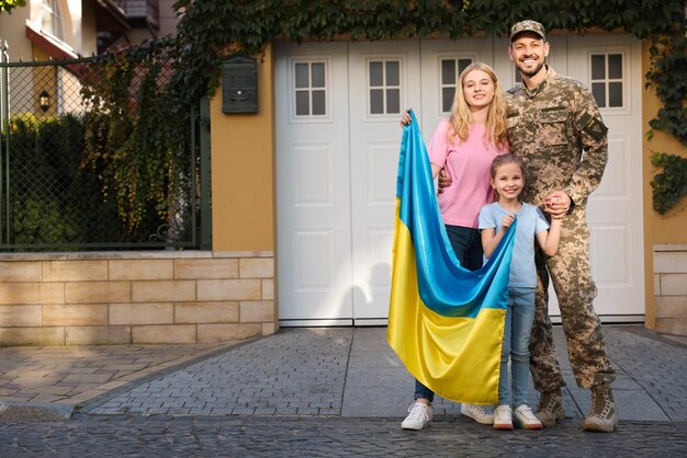 Soldat in Militäruniform wieder vereint mit seiner Familie und ukrainischer Flagge auf der Straße der Stadt Platz für Text