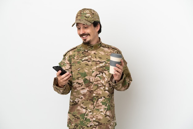 Soldat Mann isoliert auf weißem Hintergrund mit Kaffee zum Mitnehmen und einem Handy