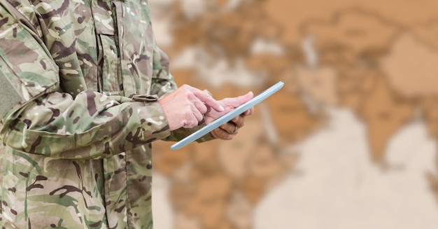 Soldat-Mittelteil mit Tablet gegen unscharfe braune Karte