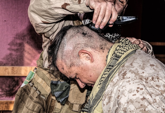 Soldat schneidet Kameraden die Haare mit Trimmer. US-Marine rasieren Freunde den Kopf mit Clipper unter Kampfbedingungen. Anwerber, der sich auf den Dienst in Streitkräften vorbereitet, indem er einen ersten Haarschnitt erhält