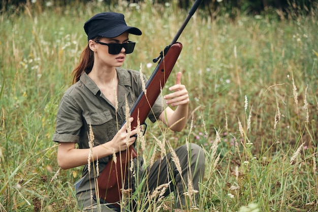 Soldatin sitzt auf der Graswaffe in den Händen einer dunklen Brille und jagt grüne Blätter