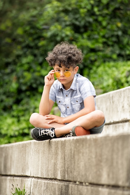 Foto solemne niño con gafas de sol amarillas