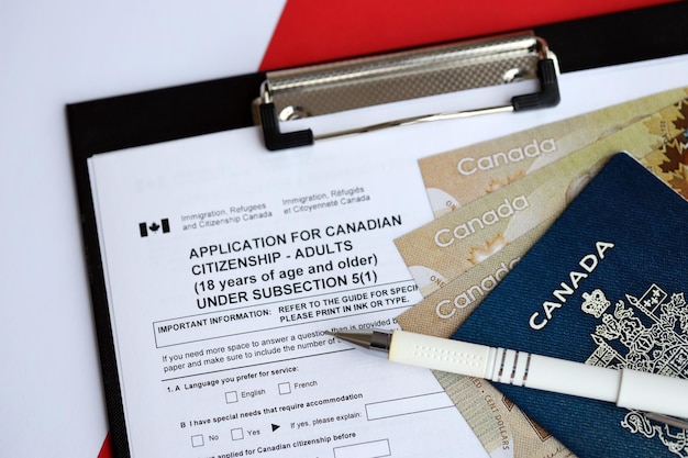 Foto solicitud de ciudadanía canadiense para adultos en la mesa con pasaporte y billetes de dólar cerrados