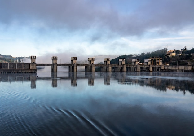 Solide Struktur des Staudamms Crestuma Lever am Fluss Douro in Portugal spiegelt sich in ruhigem Wasser wider