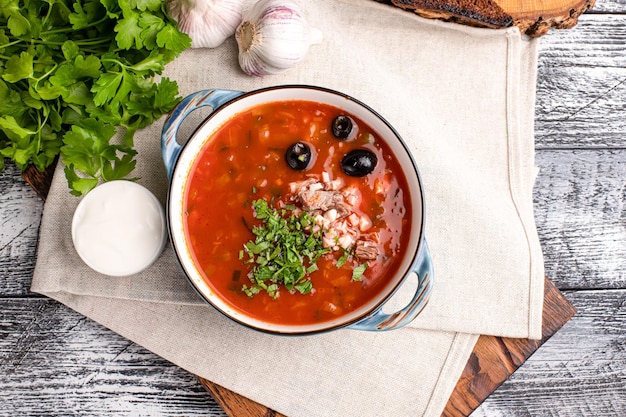 Soljanka Soljanka-Suppe mit saurer Sahne auf einem hölzernen weißen Hintergrund