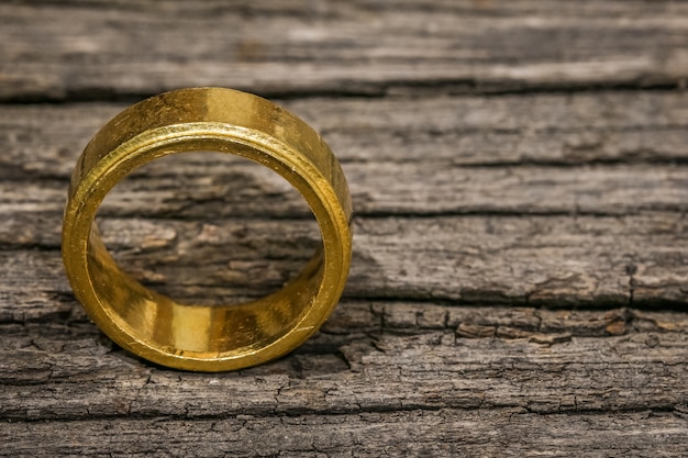 Foto un solo anillo de oro simple en la mesa de madera con espacio de copia
