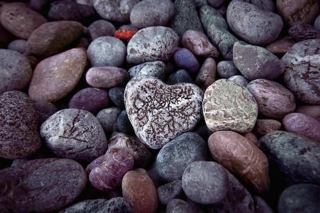 Solo corazón en piedras de guijarros negros, naturaleza muerta.