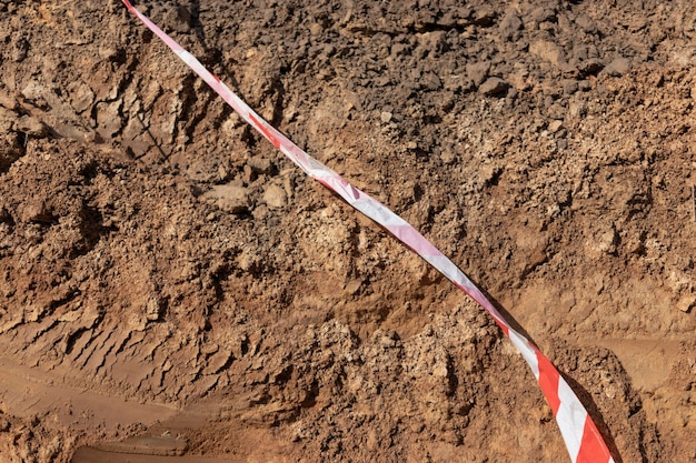 Solo na terra como textura e fundo Aviso ou fita protetora em um canteiro de obras