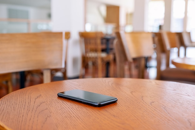 Un solo teléfono móvil negro sobre la mesa de madera