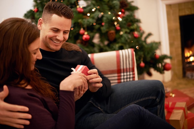 Solo para ti mi amor Una joven pareja feliz abriendo regalos el día de Navidad